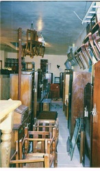 Early photo of the interior of India Street Antiques showing rows of armoires and chairs hung on the walls and hanging from the ceiling! Eventually, expansion and large racks solved the inventory display issues.