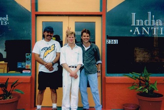 Dan, owner and founder of India Street Antiques, is pictured on the right in this photo. He is giving the "bunny ears" to his assistant pictured in the center. 

Three workers in front of the front doors of India Street Antiques on opening day, October 1, 1991.