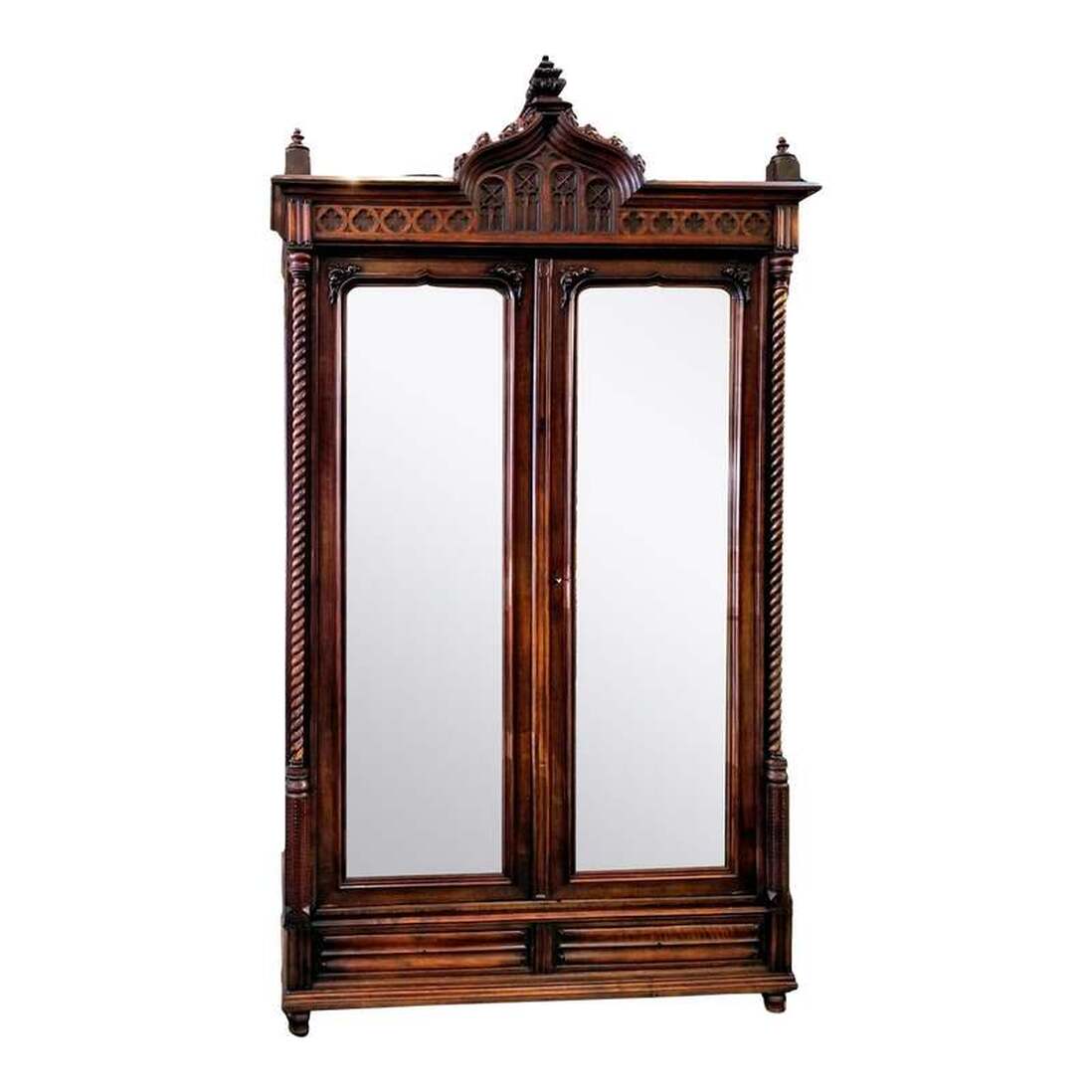 Late-Victorian ( 1896 ) armoire / wardrobe / linen press in the French Gothic style.  Built by Maison Antoine Bastet of Lyon ( ébéniste et fabricant de meubles 1864-1935 ). The House was originally established in 1845 by Andre Bastet, furniture merchant.  Antoine Bastet was a furniture maker in Lyon, France who also invented an adjustable mirror ( 1883-1905 ) and a support bra for railway travelers ( 25 April, 1902 ).  The armoire is made from walnut wood.  The decoration includes trefoils and quatrefoils on the frieze of the bonnet; sugar barley twist balusters; turned and carved finials at top; linen folds on base ends and drawer fronts; shaped front feet and block back feet; rocaille applications on bonnet and at mirror corners; flambe shapes; and beveled and shaped mirrors.  The two doors lock via a brass latch. The base drawers lock as well.  The interior has two adjustable shelves and two drawers at bottom.  The back of the armoire retains part of the original furniture label.