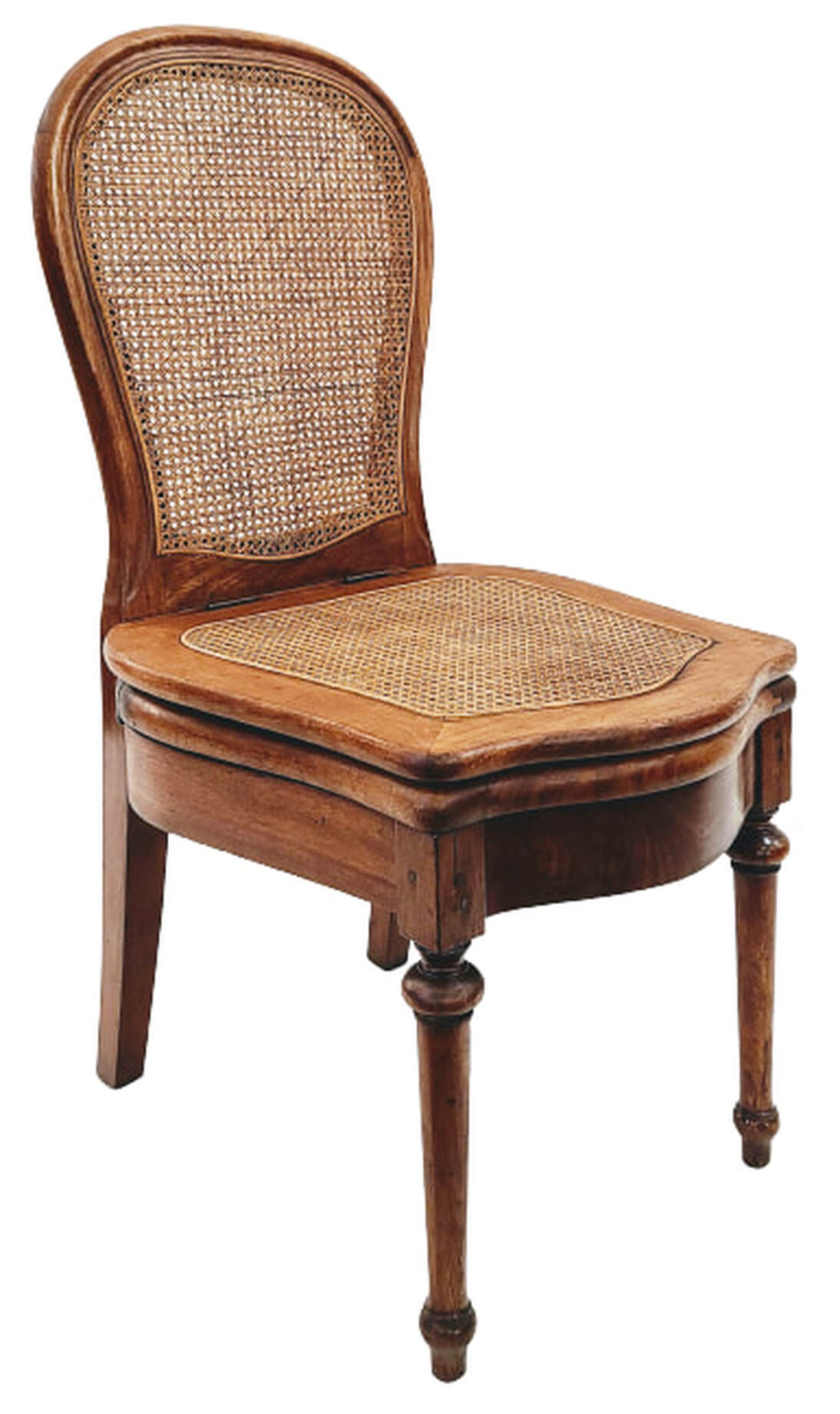 Mid-19th-century French double caned cherry wood commode chair / chaise percée / chaise nécessaire. This style of commode chair was in use approximately from the time of Louis XIV through the 1920s. This chair was manufactured in the mid-1800s, during the reigns of King Louis-Philippe, followed by Emperor Napoleon III over France and of Queen Victoria over Great Britain. The chair has a caned cartouche back, a caned curved top seat, an elegantly shaped open toilet seat, iron hinges, rear stiles ending in sabre legs, curved front and side seat rails, and ringed and tapered front legs under blocks. The chair was constructed using various joinery techniques including pegs, mortise-and-tenon, and screws. Chair may be installed in a powder room, boudoir, dining room, entry hall, or any space you require a useful conversation piece. Chair will be a comfortable addition to interiors incorporating elements of style such as French Provincial, French Country, Louis XVI, Louis XV, Louis-Philippe, Edwardian, and Victorian. SIZE: 19