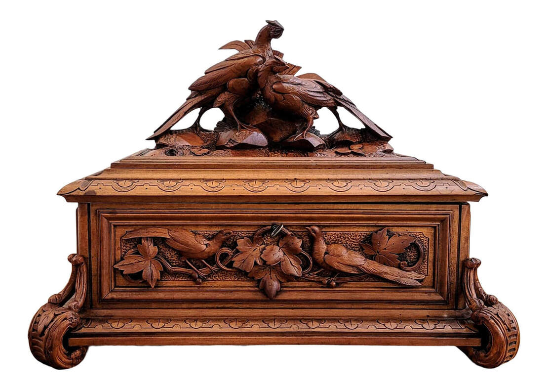 Late-19th century Swiss Schwerzwald / Black Forest carved linden wood box. The hinged lid is topped with a pair of of pheasant birds in a natural setting of earth, stone, and foliage. The front panel of the box is relief carved with a pair of pheasant birds sitting on grape vines and surrounded by grape leaves. The sides are relief carved with grapes, grape vines, and grape leaves. The back panel is plain. The top and bottom edged are trefoils and cyma curves. The box rests upon four s-curved line-carved feet into which are carved leaves and branch surface treatment. The interior is lined with cerulean blue silk fabric.