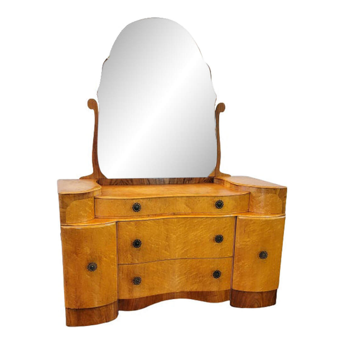The fully shaped dressing chest is built of oak wood veneered with beautiful sugar maple in bird's eye and finger curl figures. The back rail, curved stiles, elevated top platforms, plinth cabinet bases, and curved front apron are finished with burl figured walnut. The curvy chest contains one shallow jewelry drawer at top over two deep storage drawers. The drawers feature dovetail construction and serpentine fronts. The drawer interiors are built with oak and mahogany woods. At the front ends are slightly inward angled single convex door storage cabinets with one fixed shelf each. Mahogany wood lines the door interiors and is used for the molded front edges of the shelves. The cabinets surmount walnut veneered convex plinth bases. The door and drawer pulls are circular openwork molded metal with an antique patina finish. The motif is ferns, with leaves at the center and the curled fiddleheads radiating out in a circle. The back of the chest is paneled with oak wood. The shaped, beveled mirror is backed with oak wood in the shape of the mirror, and held in place with two long wooden stiles down the back. The mirror may be tilted by a finger pull at the bottom front of the mirror. SIZE: 46.25