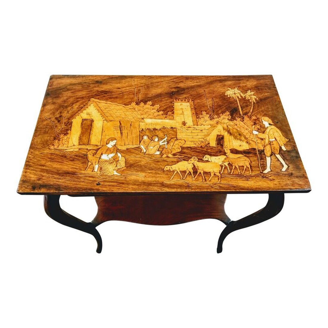 Antique rosewood parlor table with cabriole jambes (French legs that were introduced in French furniture in the late Louis XIV style) and a shaped lower shelf. The top features a sadeli (marquetry) village goat herding scene with a background showing mud architecture and a pair cooking at a pot over a fire. The scene is created with various woods and bone. Sadeli, or marquetry, is a folk art specialty of craftspeople in Surat, Gujarat, India. Surat was the first headquarters and trading outpost established by the English East India Company in 1608, which led to British Raj in India.