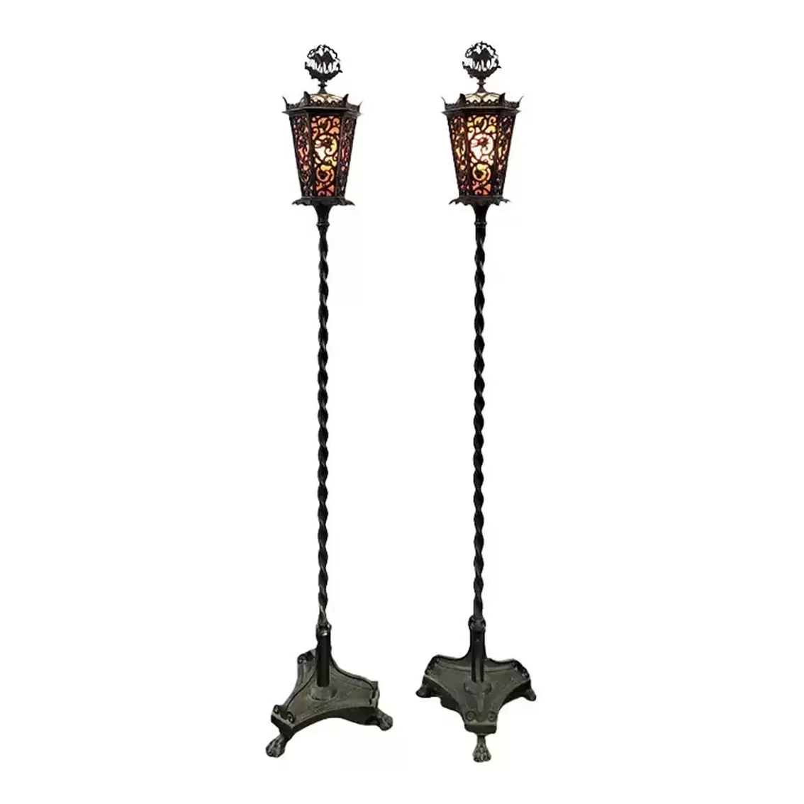 Oscar B. Bach signed torchère pair in the Henry Tudor style with Cymru/Wales dragon incorporated into the arabesque design of the lanterns.  The finials are in the image of a Tudor galleon. The tops hinge open for access to the light bulbs. The lanterns are lined with amber toned mica inserts.  The sugar barley twist poles surmount triform bases supported by paw feet.  The lights turn on by pull-chain.  The floor lamps were a 1922 release design and hand-wrought in lead and bronze in Oscar Bach's New York studio.
